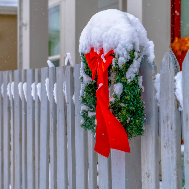istock Christmas wreath with red ribbon on picket fence 1129741599