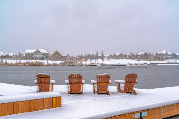istock Snowy deck with chairs overlooking lake and homes 1129745486