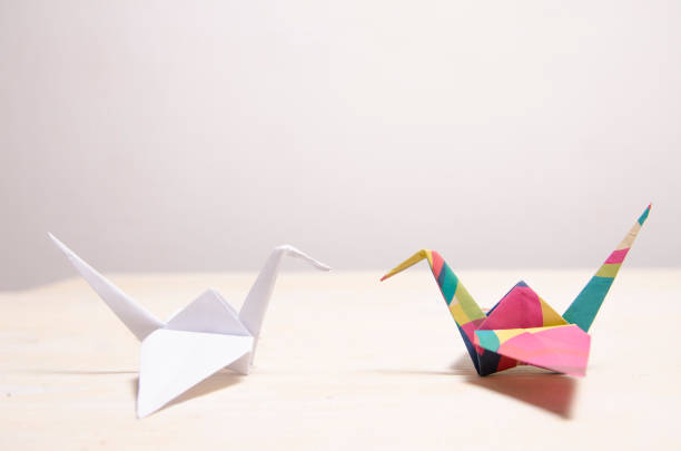 istock white origami opposite to colorful crane bird 1129748400