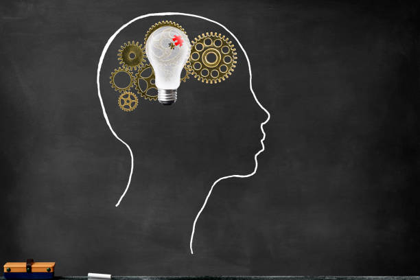 istock Metal gears inside the human head drawn with chalk, and floating light bulb 1129748496