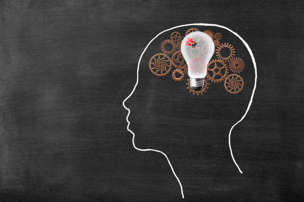 istock Metal gears inside the human head drawn with chalk, and floating light bulb 1129748523