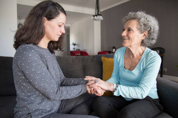 istock Elderly woman and her daughter chatting and holding hands 1129748604