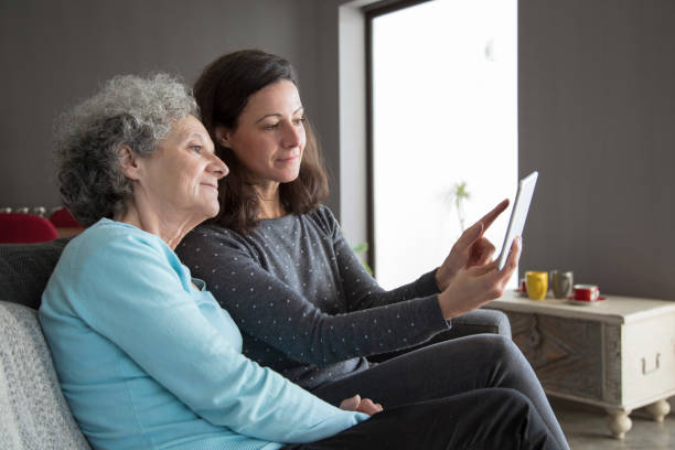 istock Elderly woman and her daughter networking on tablet computer 1129748605
