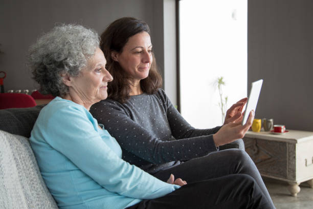 istock Focused senior woman and her daughter using tablet computer 1129748669