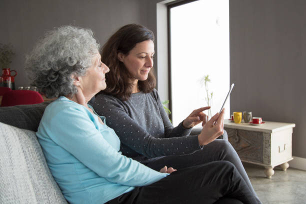 istock Serious elderly woman and her daughter browsing on tablet 1129748677