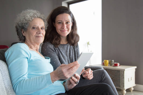 istock Smiling elderly woman and daughter browsing on tablet computer 1129748680