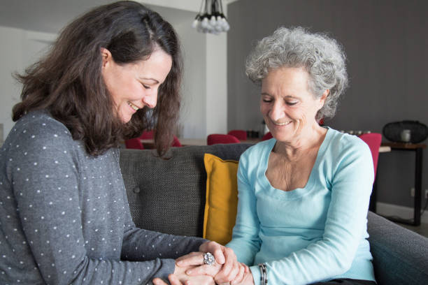 istock Smiling elderly woman and daughter chatting at home 1129748689