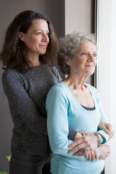 istock Calm pensive senior mother and her daughter looking out window 1129748700