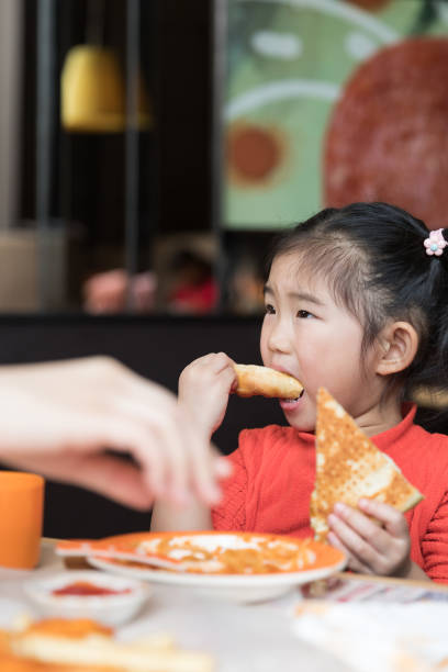 istock Cute girl eating pizza at the restaurant 1129751365