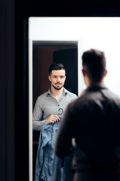 istock Stylish  Man Checking Himself in the Mirror Trying on Clothes 1129752699