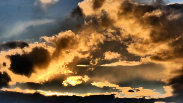 Bright orange clouds at sunset Clouds illuminated by the sun at dusk in a blue sky background reflet stock pictures, royalty-free photos & images