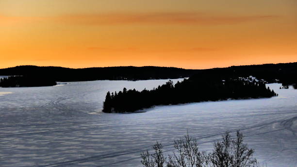 istock Orange sky on the frozen river with an island covered with forest 1129754760