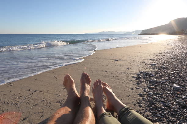 istock Detail of couples legs on beach at sunset 1129760759