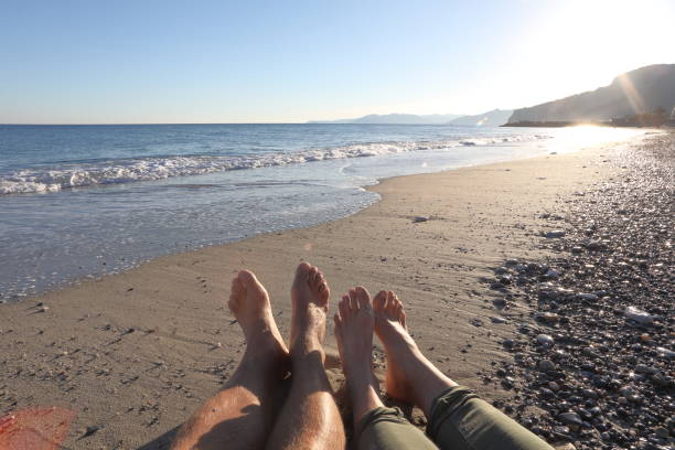 istock Detail of couples legs on beach at sunset 1129760826