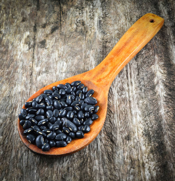 istock Black bean on wooden spoon on rustic wood background grain seeds 1129762550