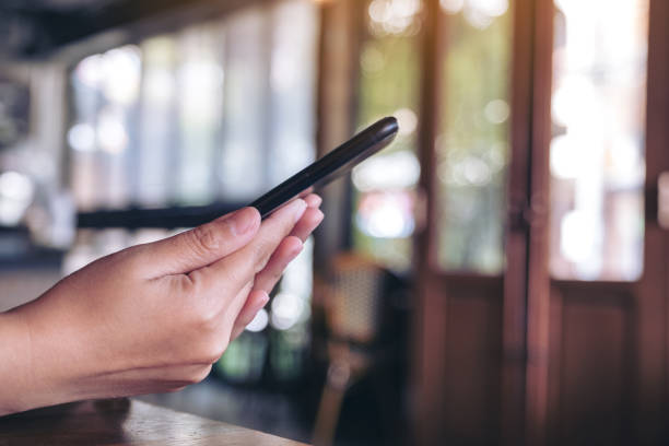 istock A woman holding and using a black smart phone 1129763356