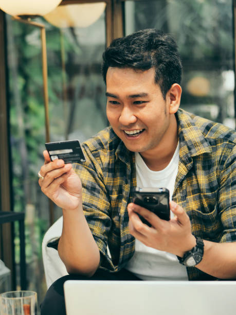 istock Asian man  making online bank transfer, man holds a credit card while entering data, lifestyle concept. 1129765106