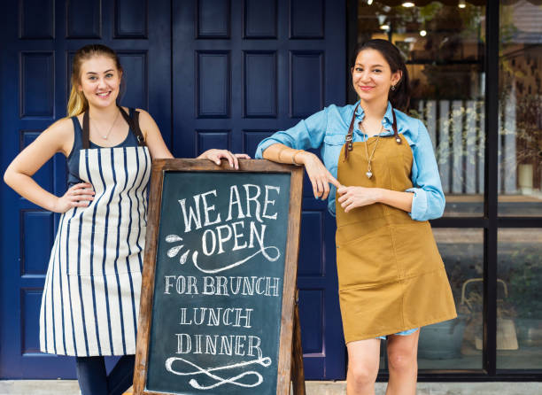 istock Cheerful business owners standing with open blackboard 1129765167