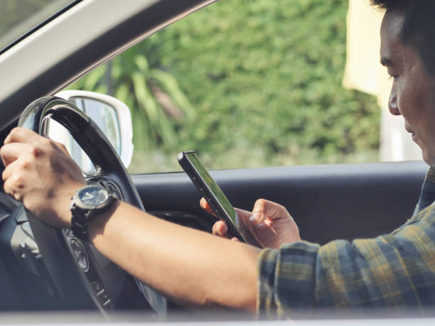 uomo asiatico che usa lo smartphone mentre guida in auto, concetto di stile di vita. - driving text messaging accident danger foto e immagini stock