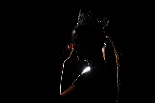 Portrait Silhouette Shadow Back Rim Light of Miss Pageant Beauty Queen Contest Silver Diamond Crown wave hand express feeling smile, studio lighting dark black background, turn side glad cry to camera