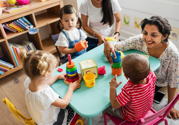istock Nursery children playing with teacher in the classroom 1129769305