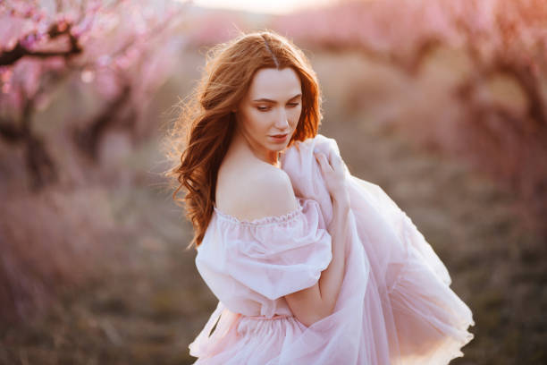 istock Beautiful young girl under the flowering pink tree 1129770991