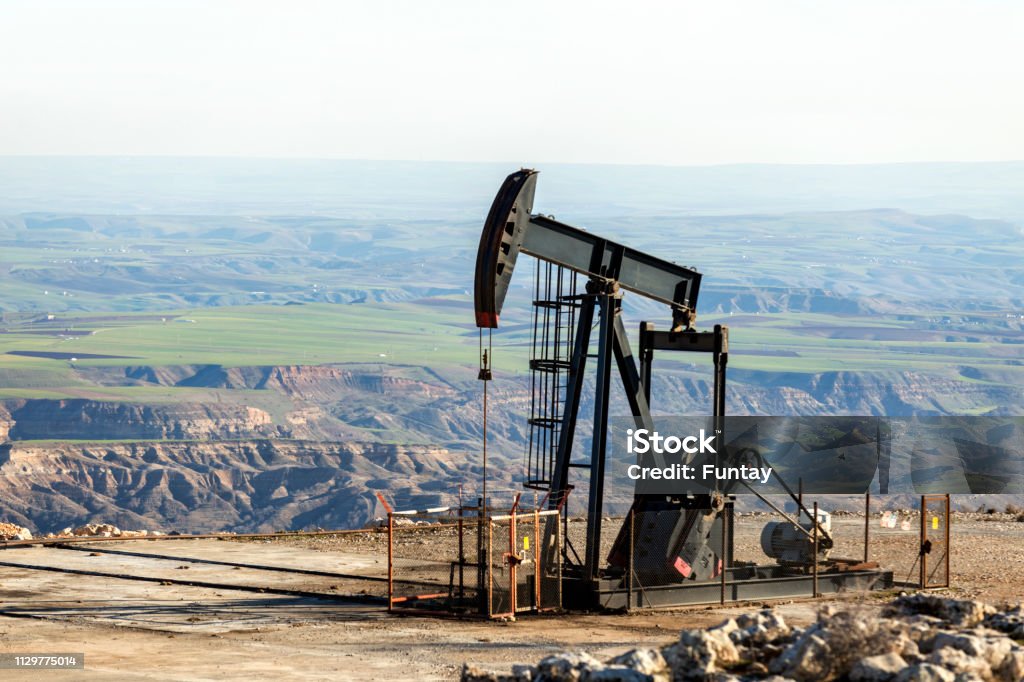 Vue de la pumpjack dans le puits de pétrole du champ d'huile. L'agencement est couramment utilisé pour les puits terrestres produisant peu d'huile. Les Pumpjacks sont fréquents dans les zones riches en pétrole. - Photo de Pétrole libre de droits