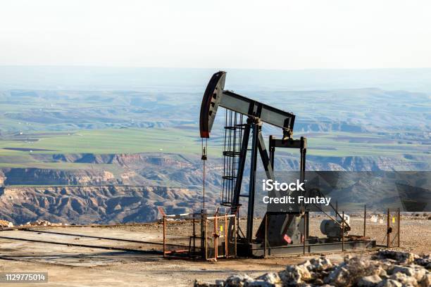 Photo libre de droit de Vue De La Pumpjack Dans Le Puits De Pétrole Du Champ Dhuile Lagencement Est Couramment Utilisé Pour Les Puits Terrestres Produisant Peu Dhuile Les Pumpjacks Sont Fréquents Dans Les Zones Riches En Pétrole banque d'images et plus d'images libres de droit de Pétrole