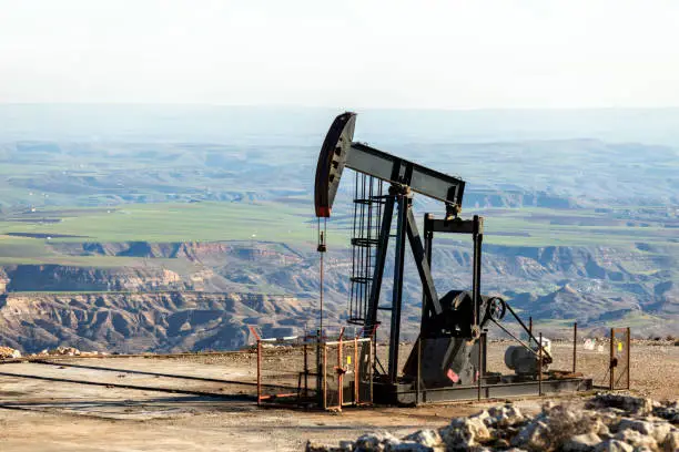 Photo of View of the pumpjack in the oil well of the oil field. The arrangement is commonly used for onshore wells producing little oil. Pumpjacks are common in oil-rich areas.