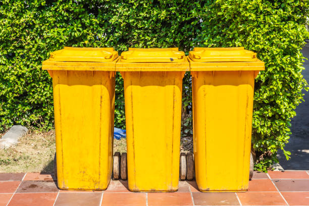 istock Row of yellow plastic trash bin for wate separation and recycling on green leaf background 1129777122