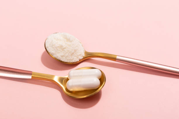 Collagen powder and pills on pink background Collagen powder and pills on pink background. Extra protein intake. Natural beauty and health supplement for skin, bones, joints and gut. Plant or fish based. Flatlay, top view. Copy space for your text. human collagen stock pictures, royalty-free photos & images