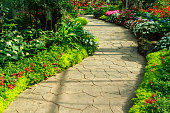 istock Stone walkway in flower garden. 1129781599