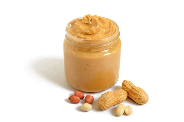 Peanut butter in a glass jar with peanuts isolated on white background.  A traditional product of American cuisine. Peanut butter in a glass jar with peanuts isolated on white background.  A traditional product of American cuisine. peanutbutter stock pictures, royalty-free photos & images