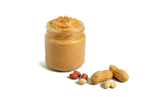 istock Peanut butter in a glass jar with peanuts isolated on white background.  A traditional product of American cuisine. 1129787921