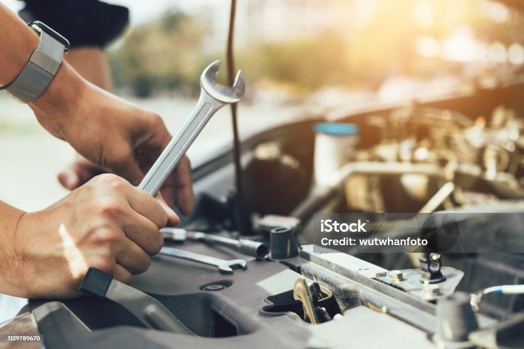 Car mechanic is holding a wrench ready to check the engine and maintenance. Auto Repair Shop Stock Photo