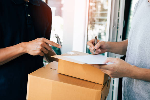 istock Delivery employee transport parcels pointing to documents for customers to receive products. 1129789766
