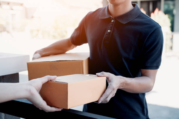 istock Close up of hands cargo staff are delivering cardboard boxes with parcels inside to the recipient's hand. 1129789778