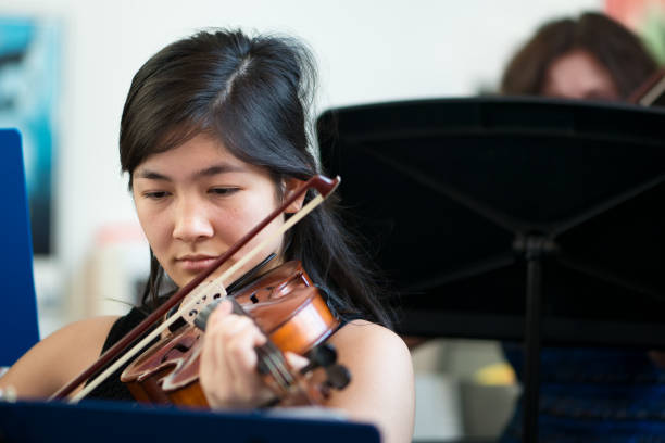 ragazza adolescente di etnia mista che suona il violino in classe di gruppo - band name immagine foto e immagini stock