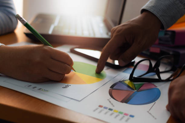 istock Two colleagues discussing and planing together with trade data chart document on office desk. 1129790800