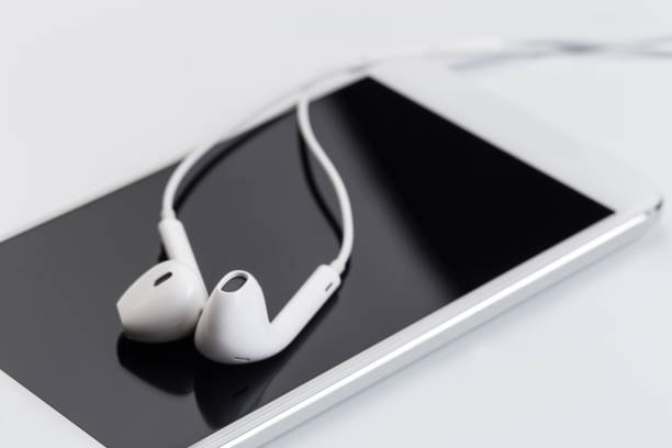 istock white earphones on white keyboard with phone 1129792068