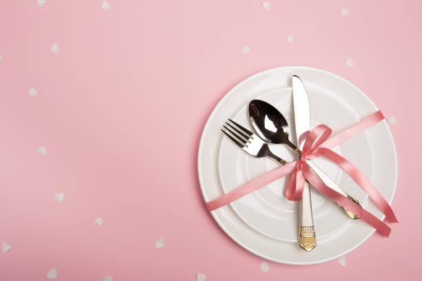 istock Festive table setting for Valentine's Day with fork, knife,  hearts on a red background. Top view. - Image 1129792415