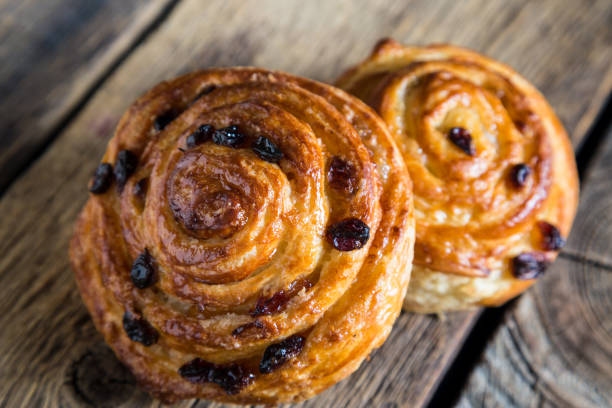 istock Fresh buns with raisins on a wooden table 1129794615