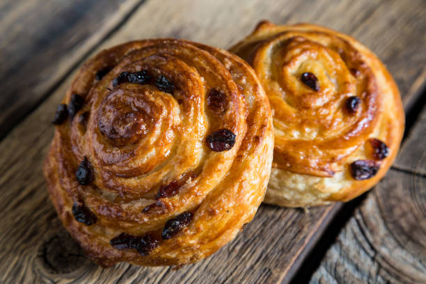 istock Fresh buns with raisins on a wooden table 1129794647