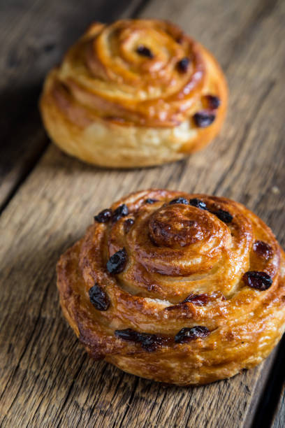 istock Fresh buns with raisins on a wooden table 1129794662