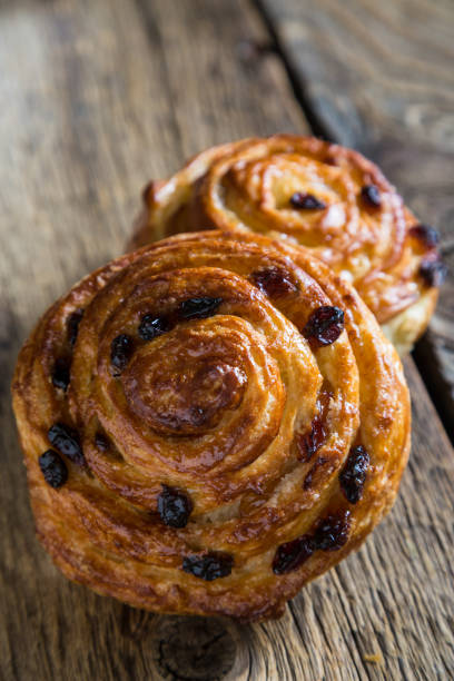 istock Fresh buns with raisins on a wooden table 1129794676