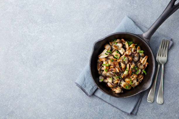 Fried mushrooms with fresh herbs in black cast iron pan. Top view. Copy space
