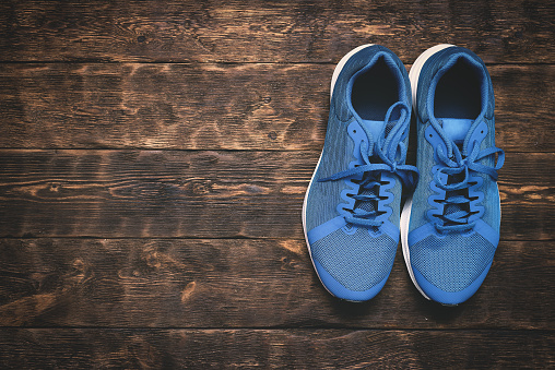 Pair of sports shoes on a wooden floor background with copy space.