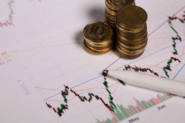 istock Pen on a colourful diagram. Coins in the background. 1129797095
