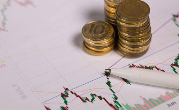 istock Pen on a colourful diagram. Coins in the background. 1129797142