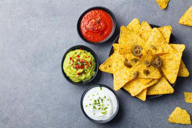nachos chips on a plate with sauces, dip variety. grey stone background. top view. copy space. - chili food bowl ready to eat imagens e fotografias de stock